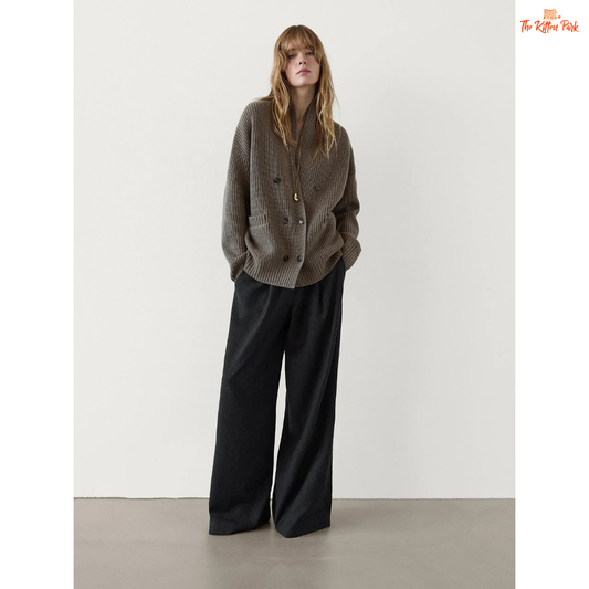 Woman wearing a gray textured sweater and black wide-leg pants against a white background