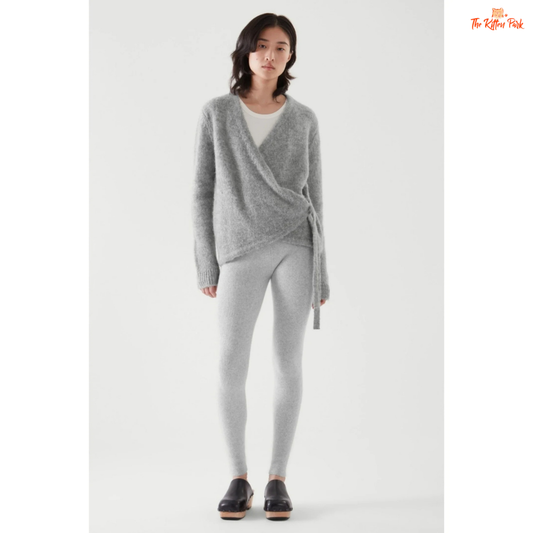 Woman wearing a gray knit cardigan and leggings on a white background