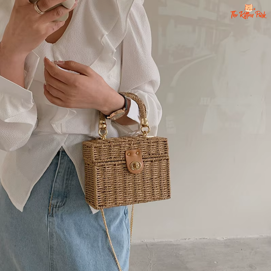 Woven rattan box-shaped summer purse with chain strap and lock detail, ideal for beach or boho-style outfits.