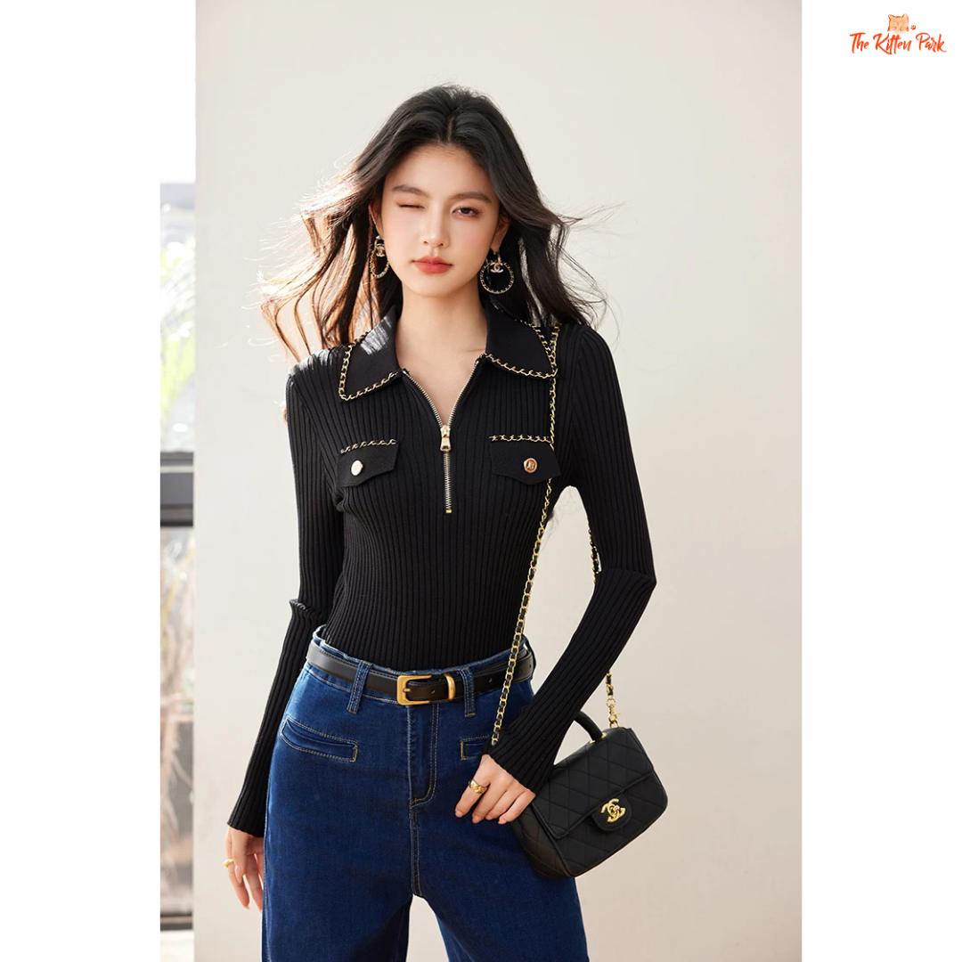 Woman wearing a black outfit with a gold chain and carrying a black handbag.