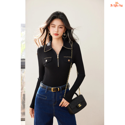 Woman wearing a black outfit with a gold chain and carrying a black handbag.