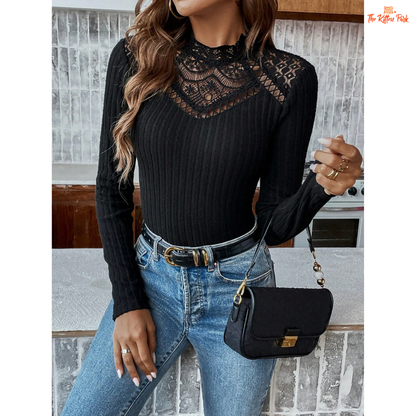 Woman wearing a black ribbed sweater with lace details and blue jeans, holding a black handbag.