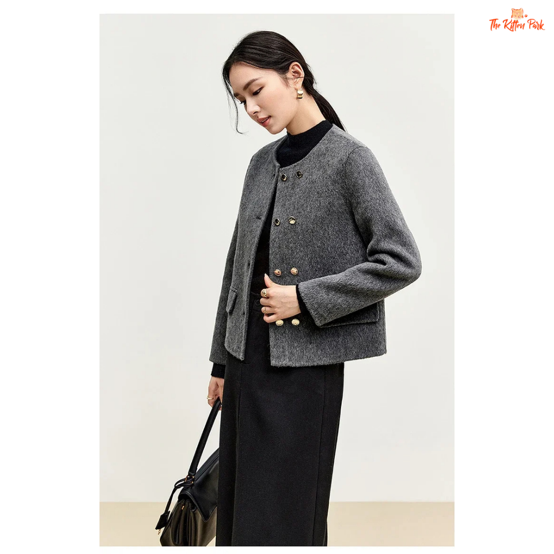 Woman wearing a gray coat with gold buttons on a plain background