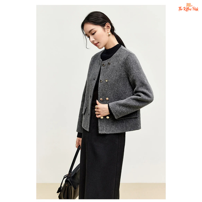 Woman wearing a gray coat with gold buttons on a plain background