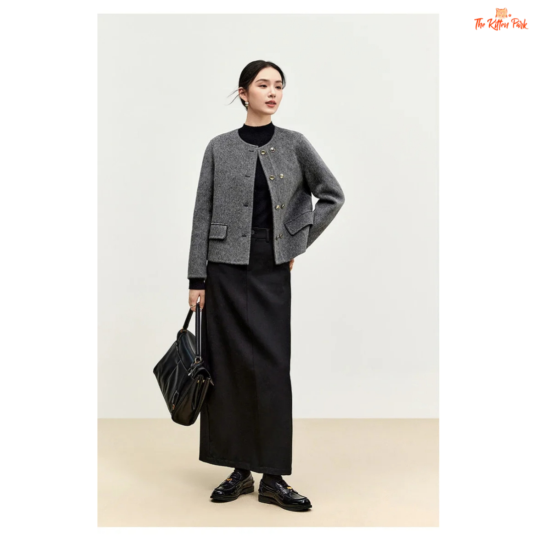 Woman wearing a gray jacket and black skirt holding a black bag on a white background