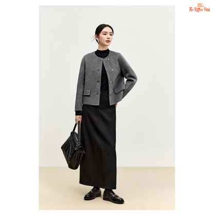 Woman wearing a gray jacket and black skirt holding a black bag on a white background