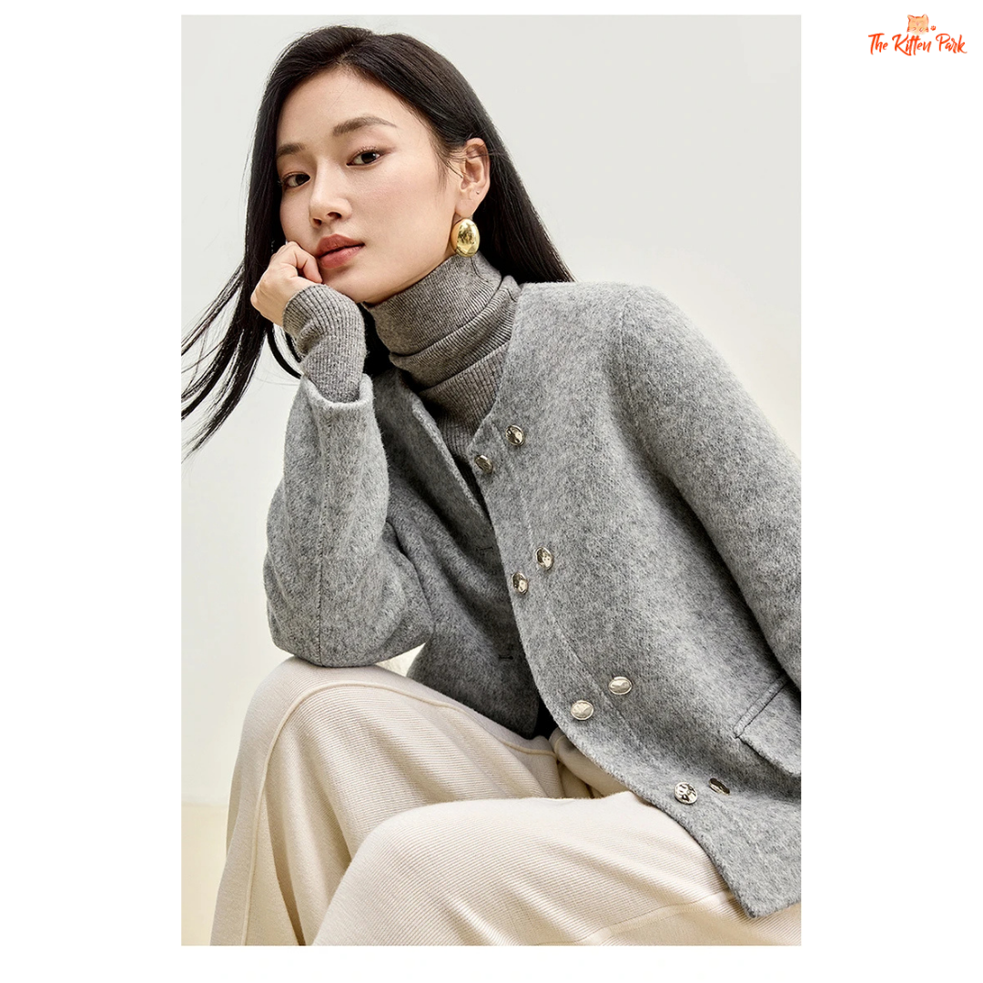 Woman wearing a gray turtleneck sweater and coat against a white background