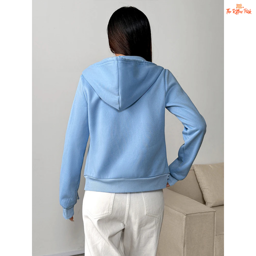 Person wearing a light blue hoodie in a minimal indoor setting