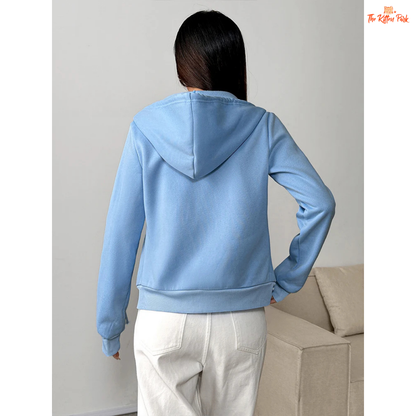 Person wearing a light blue hoodie in a minimal indoor setting