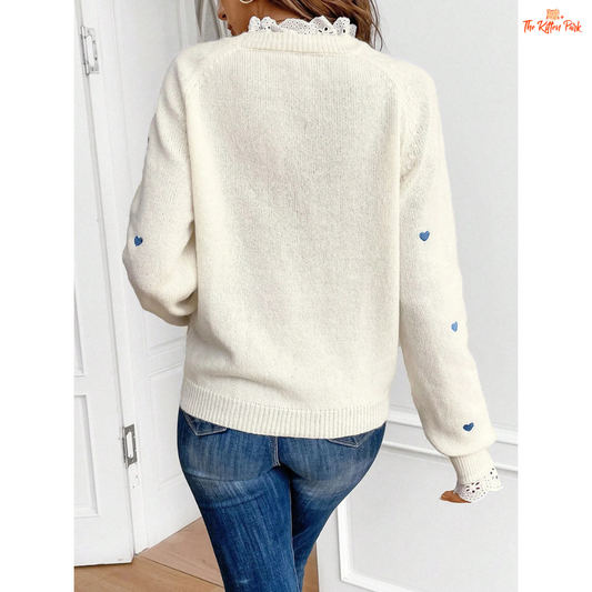 A soft ivory knit pullover featuring lace-trim heart embroidery, round neck, and regular fit for an elegant autumn-winter look.