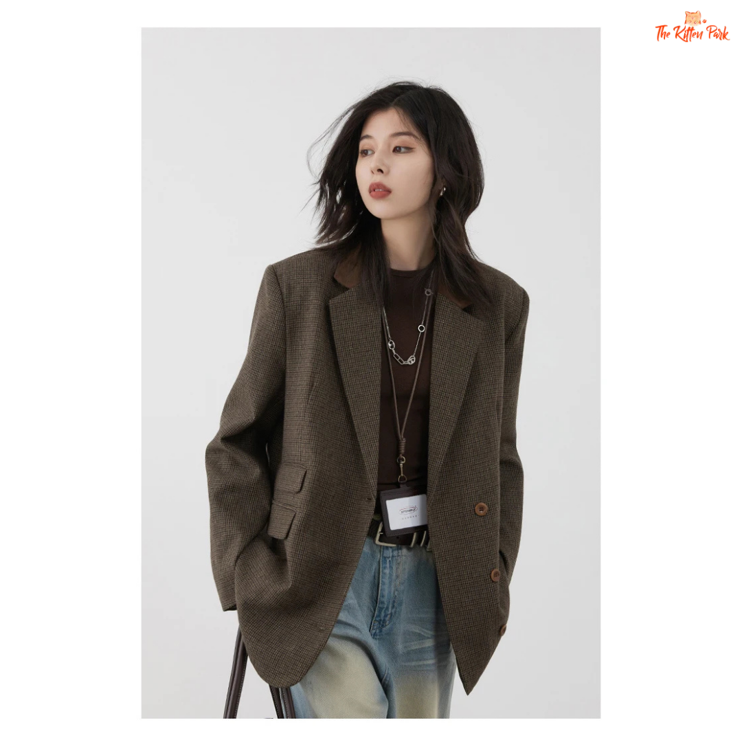 Woman wearing a brown blazer over a dark top with light blue jeans on a white background