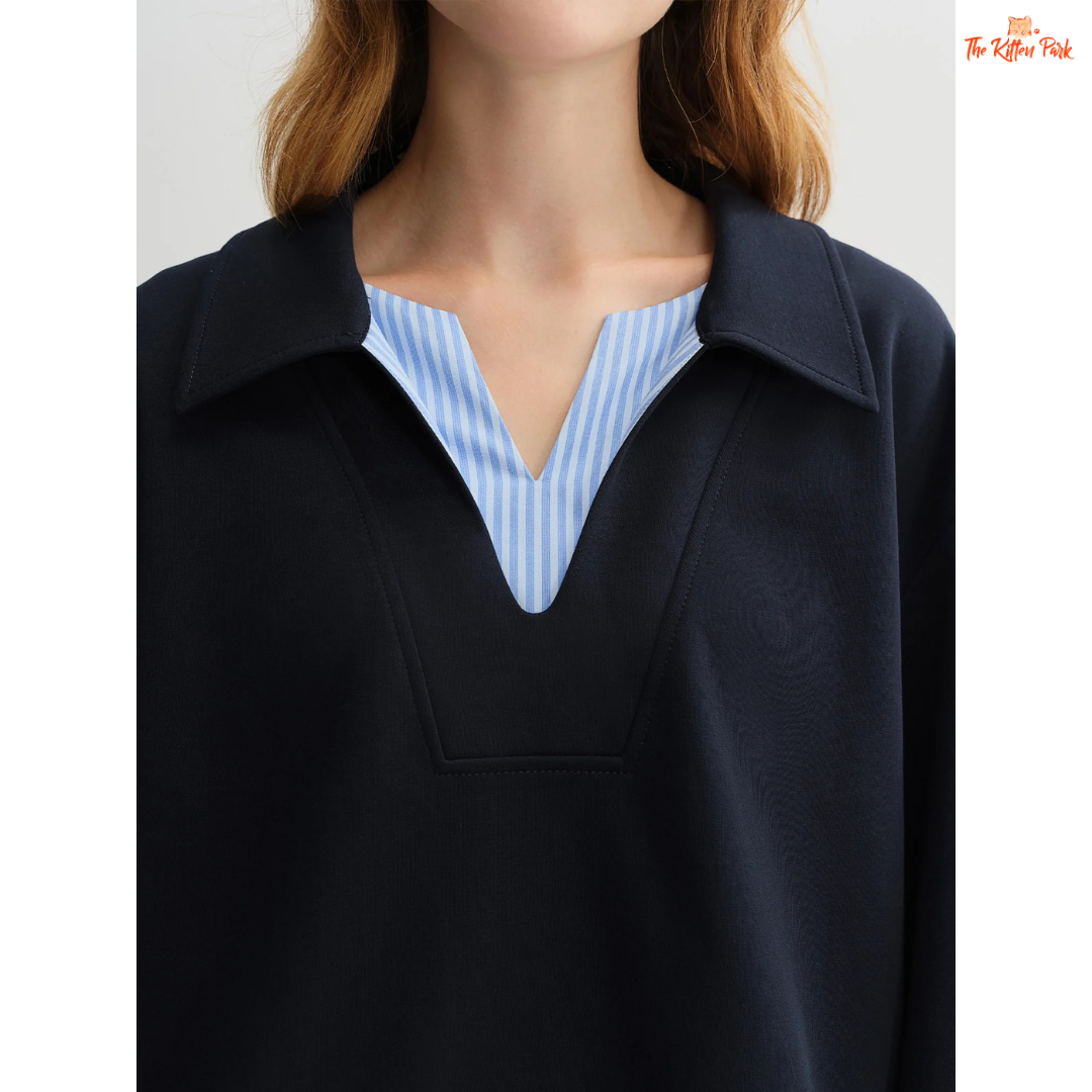 Person wearing a black jacket over a blue and white striped shirt on a plain background