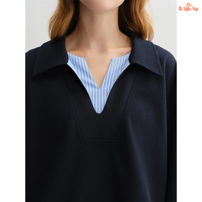 Person wearing a black jacket over a blue and white striped shirt on a plain background