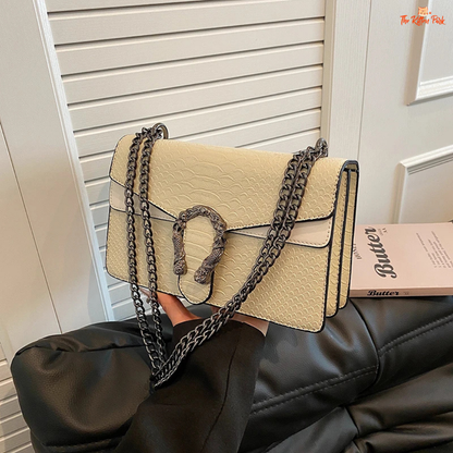 Small square crossbody bag with retro snake pattern, chain strap, hard shell body, and zippered interior for a bold fashion statement.