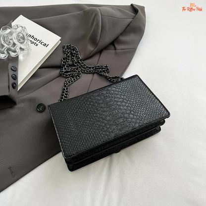 Small square crossbody bag with retro snake pattern, chain strap, hard shell body, and zippered interior for a bold fashion statement.