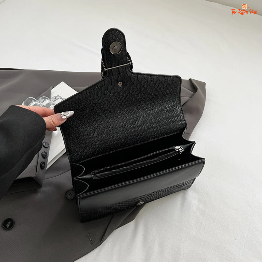 Small square crossbody bag with retro snake pattern, chain strap, hard shell body, and zippered interior for a bold fashion statement.