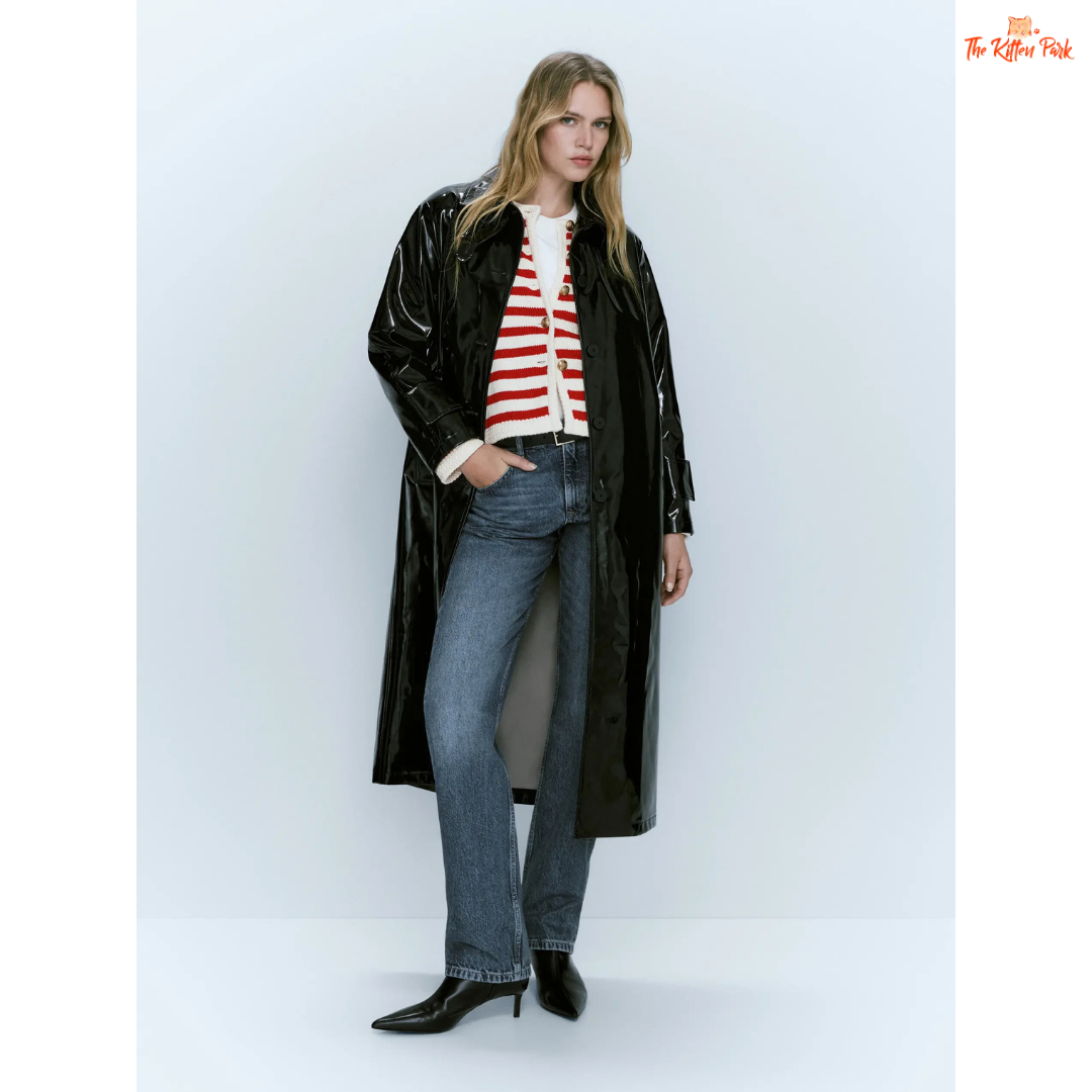 Woman wearing a black coat, striped sweater, and jeans on a white background