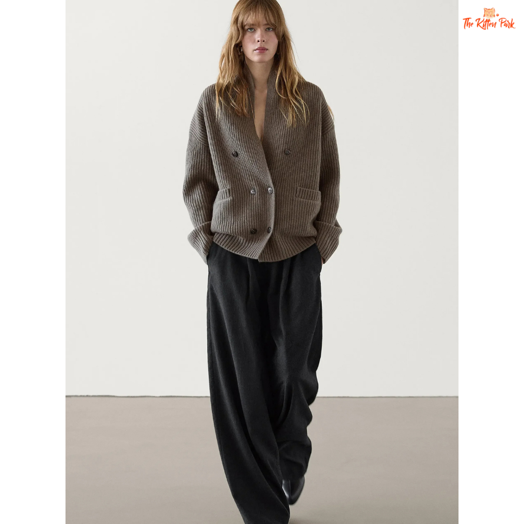 Woman wearing a gray knitted cardigan and black pants on a white background