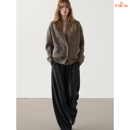 Woman wearing a gray knitted cardigan and black pants on a white background