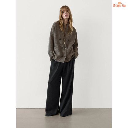 Woman wearing a gray textured sweater and black wide-leg pants against a white background