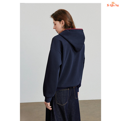 Person wearing a navy blue hoodie and jeans on a plain background