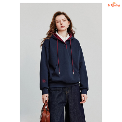 Person wearing a navy hoodie with red drawstrings on a plain background