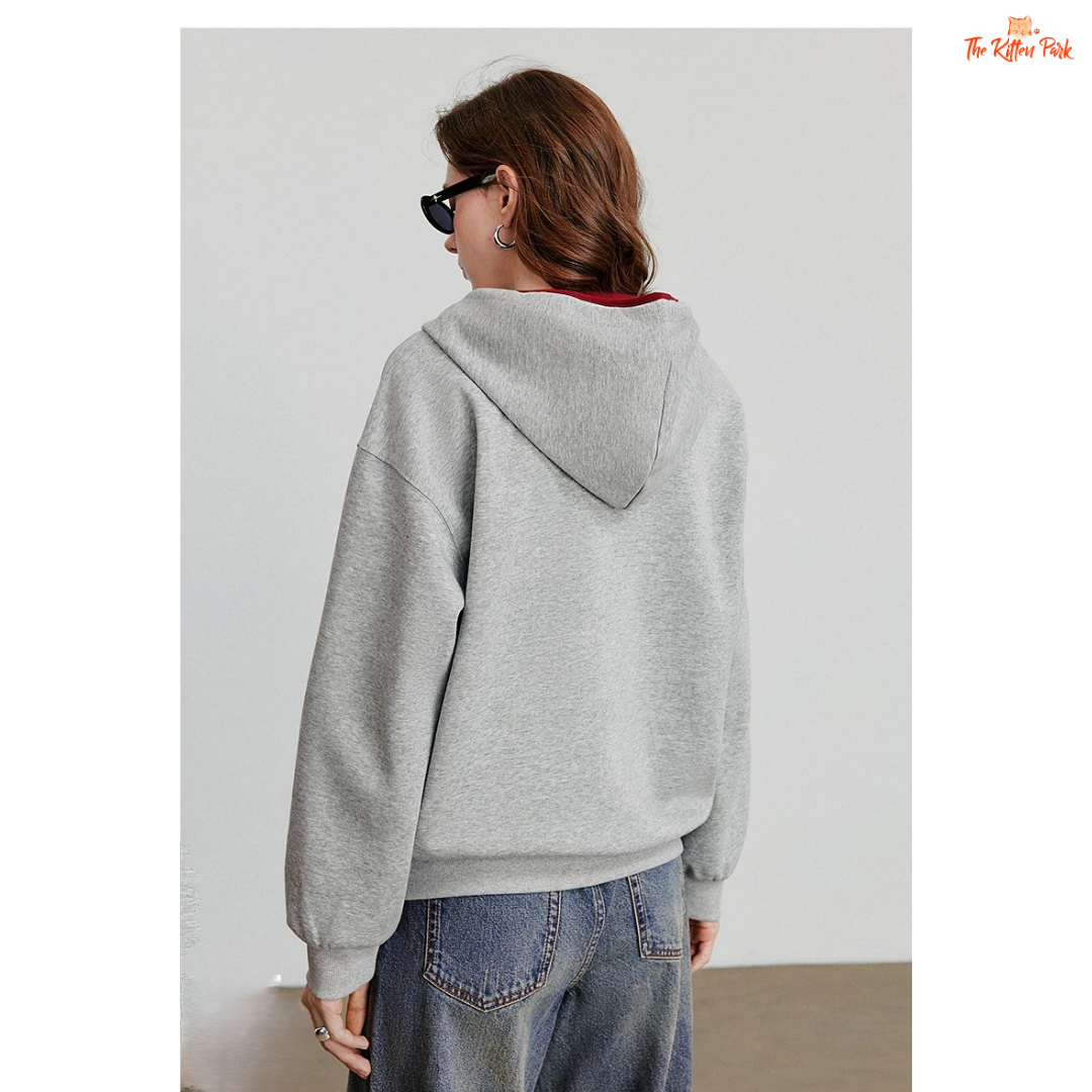 Person wearing a gray hoodie and blue jeans against a plain background