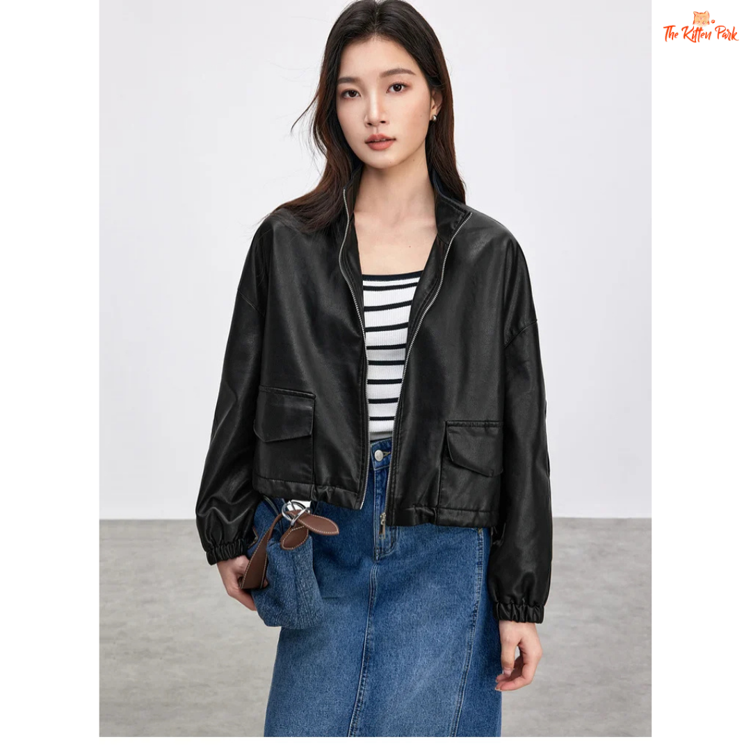 Woman wearing a black leather jacket over a striped shirt and blue jeans on a plain background