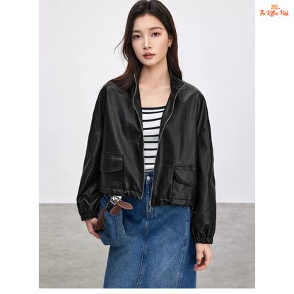 Woman wearing a black leather jacket over a striped shirt and blue jeans on a plain background