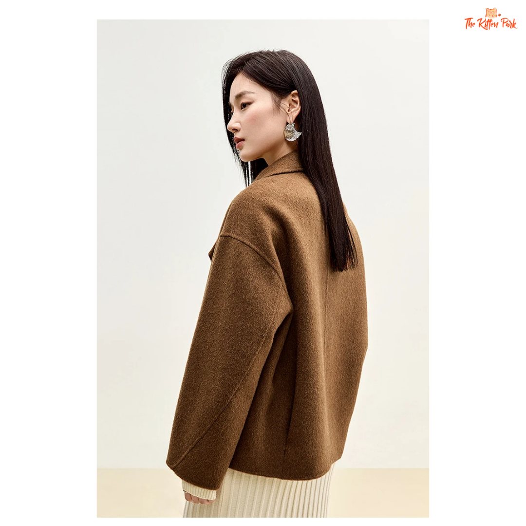 Women’s short wool coat in thick fabric with camel wool blend, double-breasted closure, drop-shoulder sleeves, and turn-down collar for winter wear.