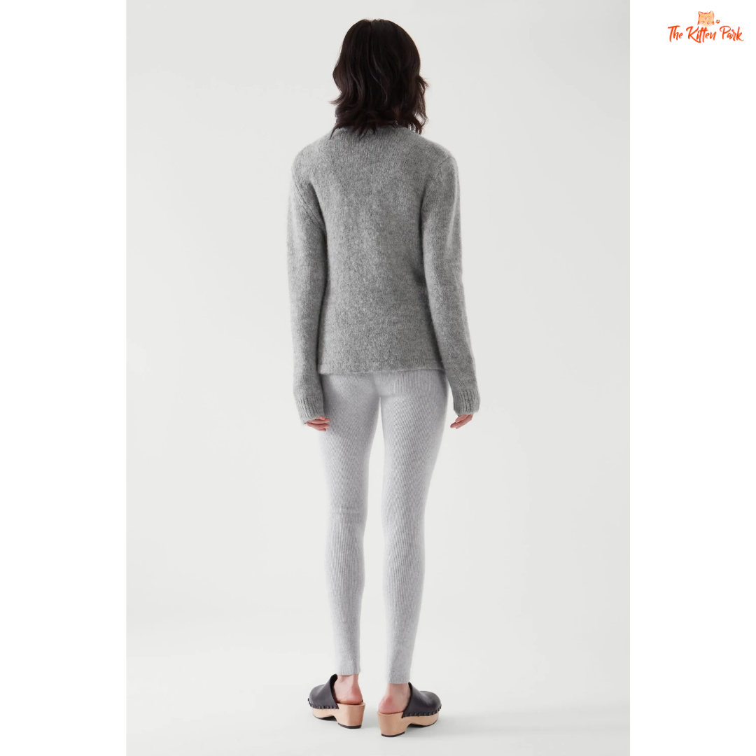 Woman wearing a gray sweater and pants on a white background