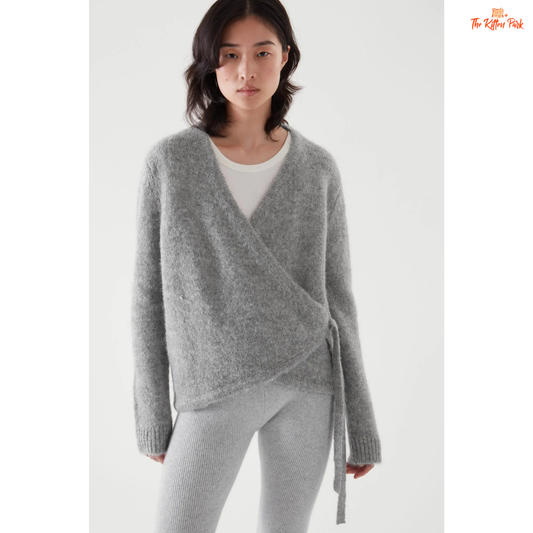 Woman wearing a gray wrap sweater over a white shirt on a white background