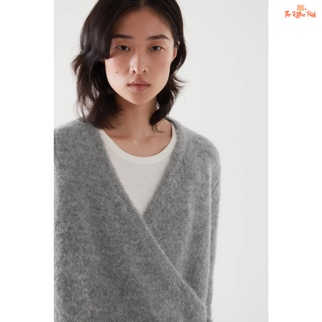 Woman wearing a gray sweater over a white shirt on a white background