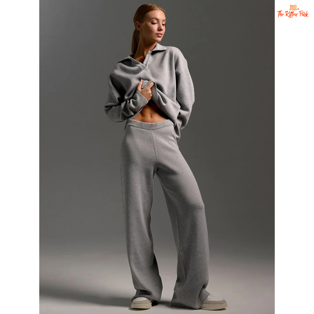 Woman wearing a gray sweater and pants on a plain background